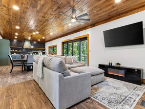A modern living room with a sectional sofa, a flat-screen TV, and a fireplace. - Sleeps 20 + Indoor Pool + Game Room Near Pigeon Forge | Spurling Retreat (Sevierville)