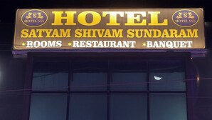A sign for Hotel Satyam Shivam Sundaram, indicating it offers rooms, a restaurant, and a banquet.