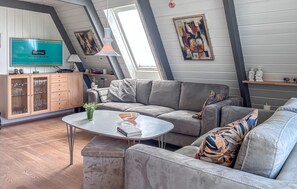 A modern living room with a grey sofa, a coffee table, and a TV mounted on the wall. - Gorgeous home in Farsø with WiFi (Farsø)