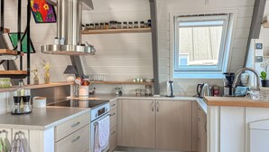 Et kompakt køkken med indbygget ovn, et vindue og et udvalg af redskaber og hårde hvidevarer.