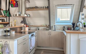 A compact kitchen with a built-in oven, a window, and a variety of utensils and appliances. - Gorgeous home in Farsø with WiFi (Farsø)