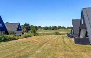 A row of modern, triangular-roofed buildings with a well-maintained lawn in the foreground.