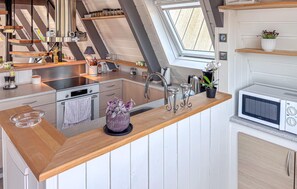 A modern kitchen with a wooden countertop, stainless steel appliances, and a skylight.