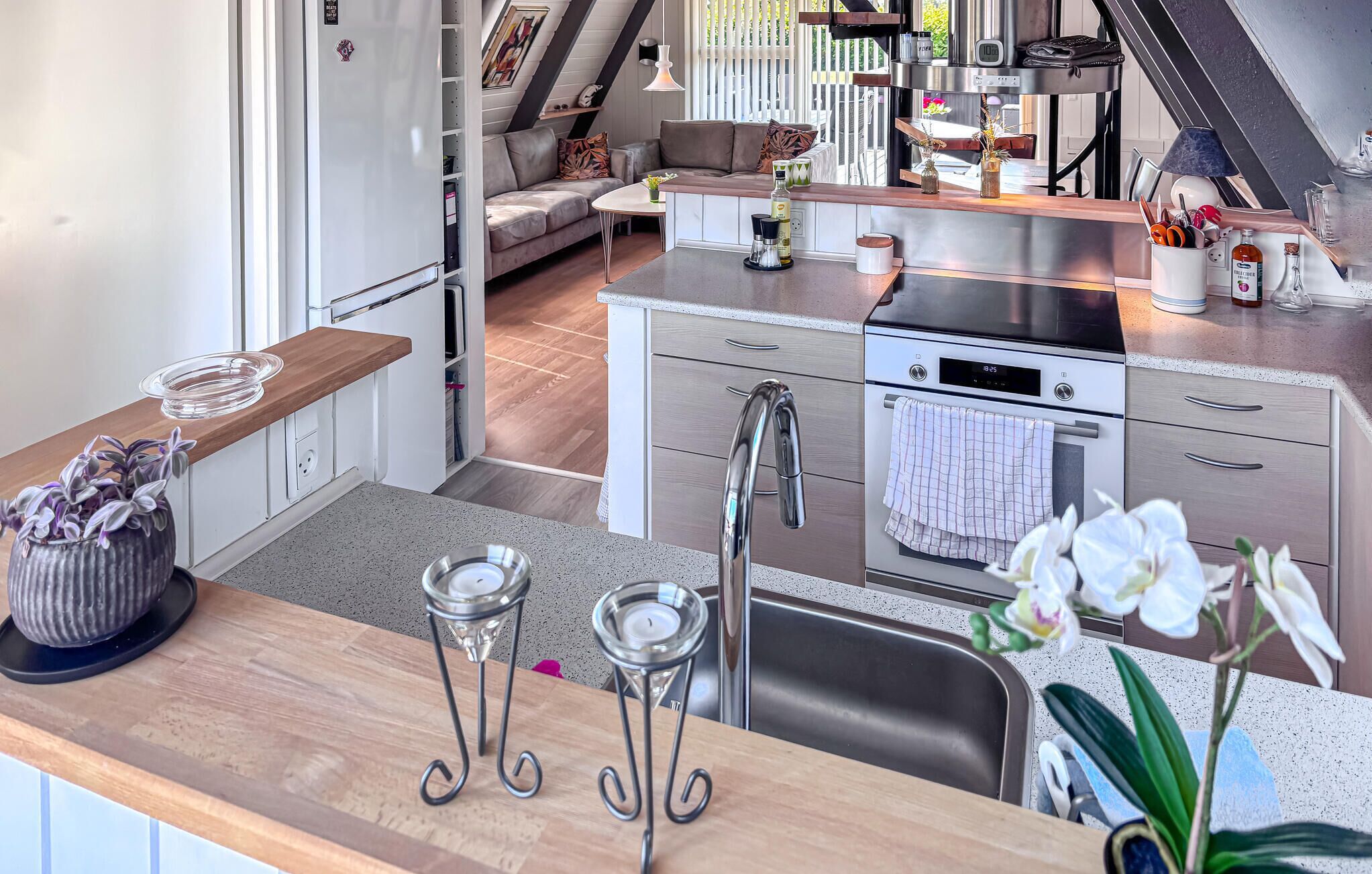 Una cocina moderna con un lavamanos de acero inoxidable, un horno empotrado y una encimera con un florero.