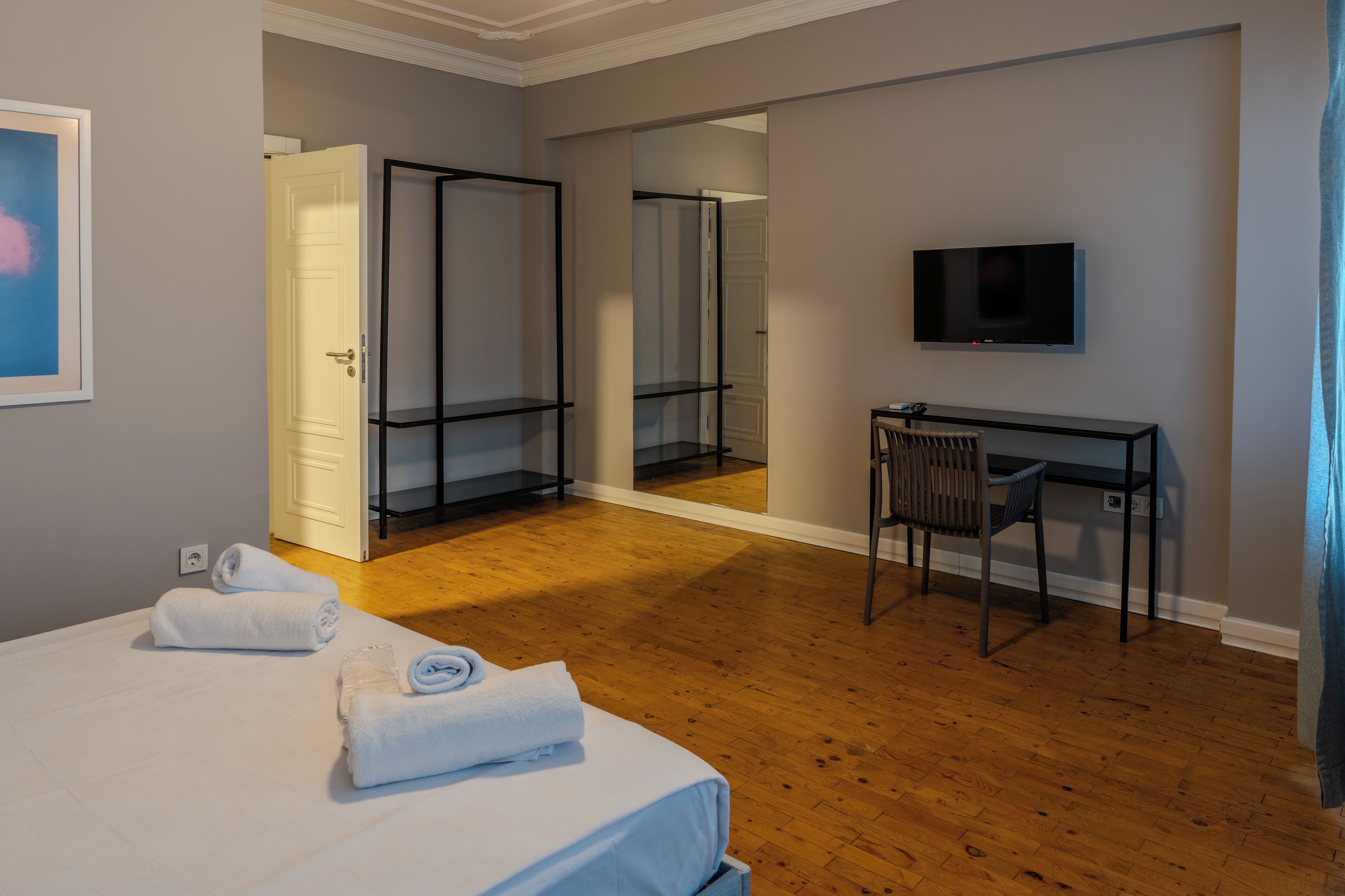 A hotel room with a bed, a desk, a chair, a television, and a mirror.