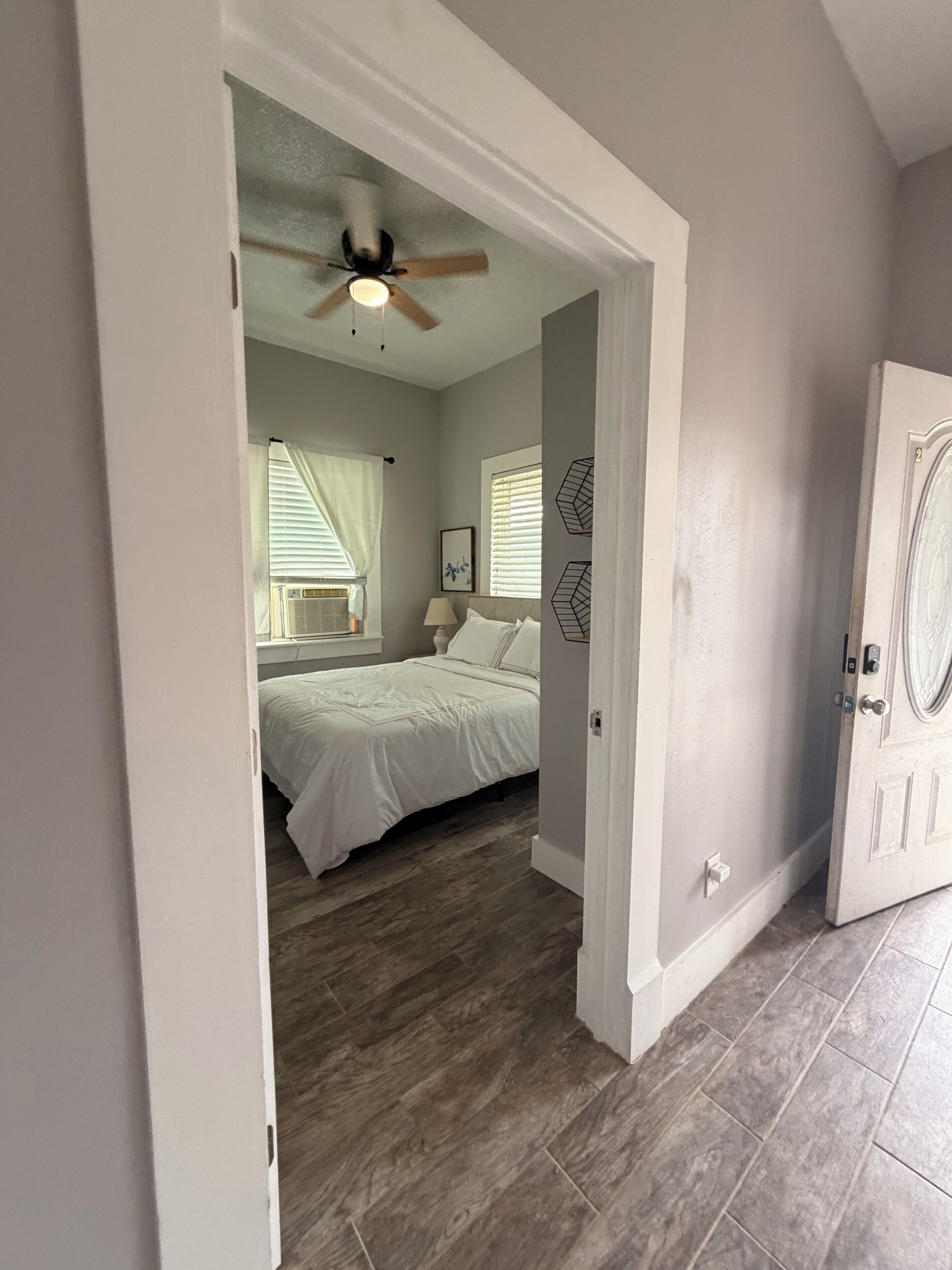A bedroom with a bed, a ceiling fan, and a window with blinds.