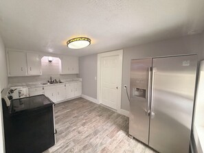 Eine Küche mit weißen Schränken, einem Edelstahlkühlschrank und einem eingebauten Backofen.
