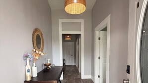 A hallway with a wooden floor, a hanging light fixture, a mirror, and a table with decorative items. -         Modern 2BR- gated Duplex -Sleeps 7 - Free Parking - Near Downtown (Houston)