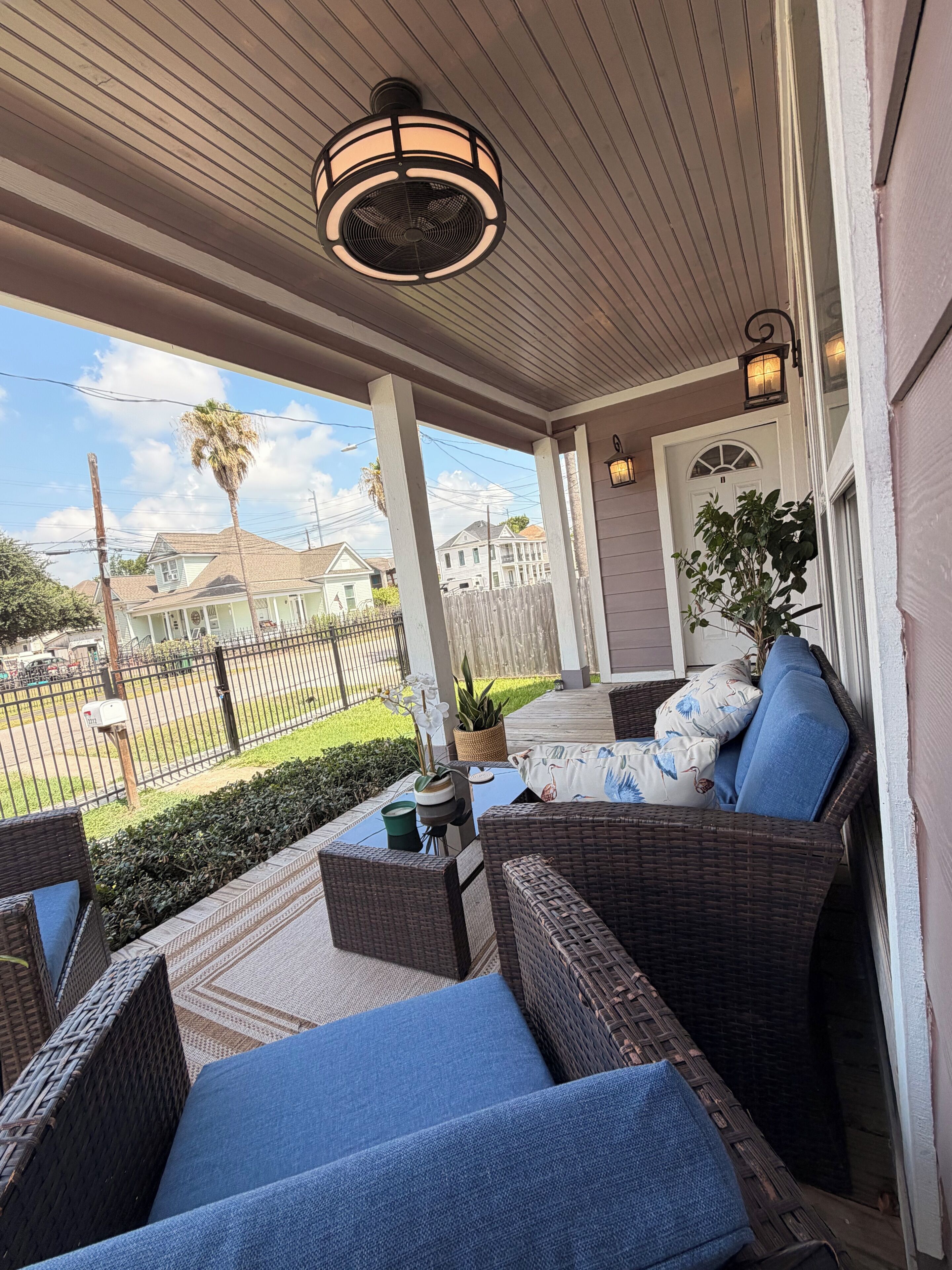 A covered porch with wicker furniture and a view of a residential street.