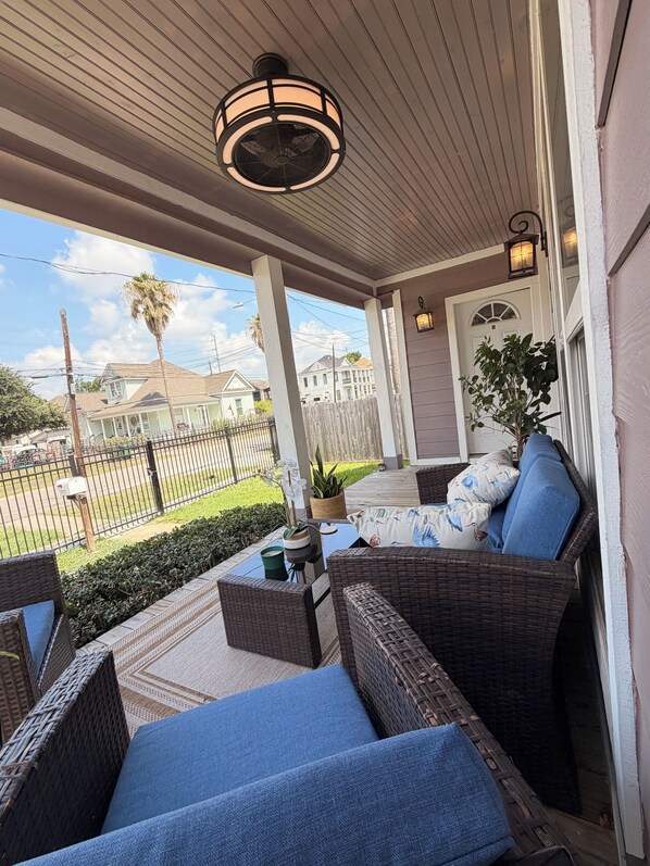 A covered porch with wicker furniture and a view of a residential street.