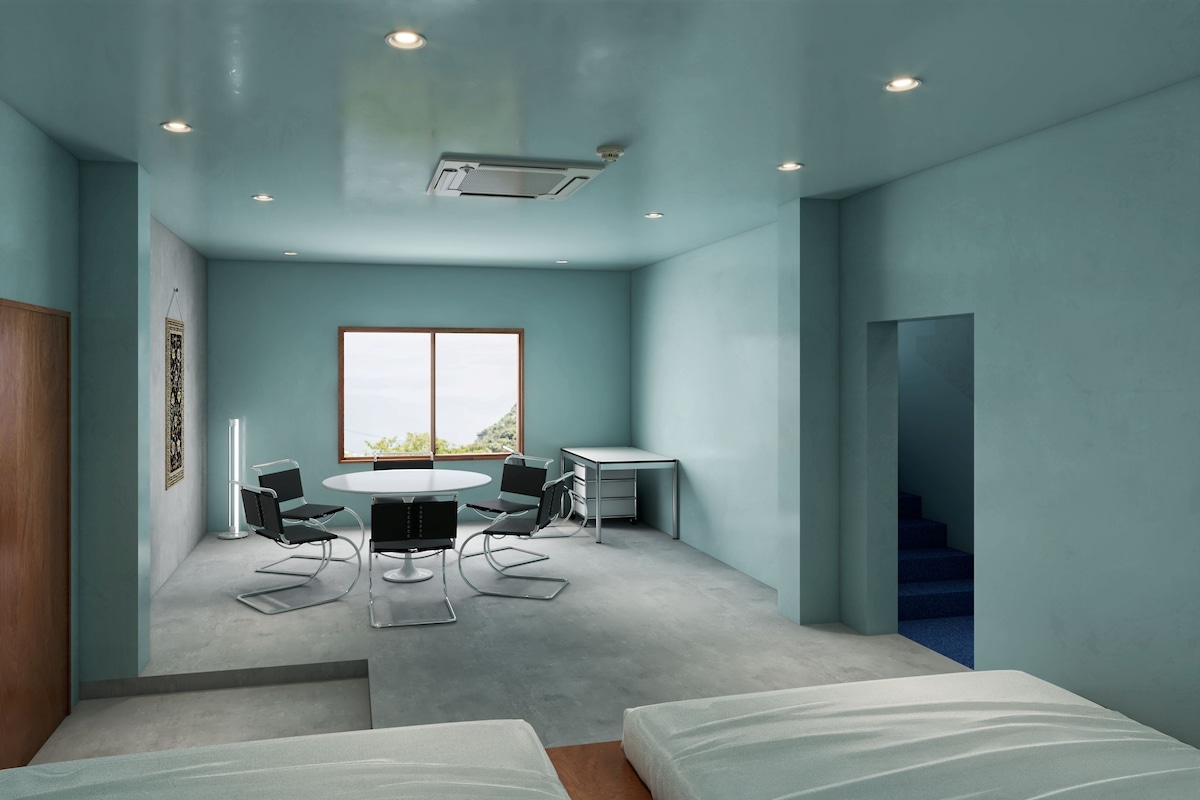 A modern room with a round table, chairs, a desk, and a bed.