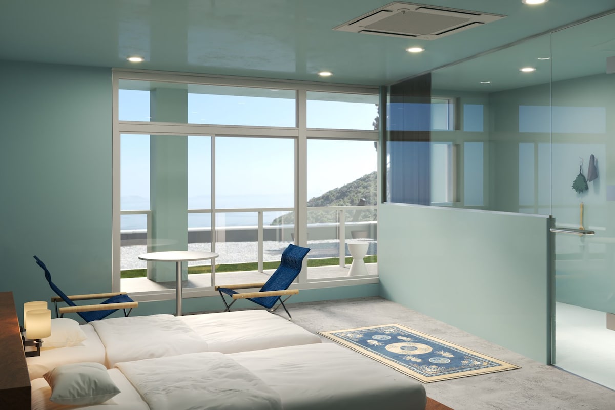A modern hotel room with a large window, a bed, a chair, and a small table.