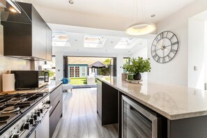 Una cocina moderna con una isla grande, estufa integrada y un reloj en la pared.