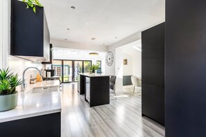 Una cocina moderna con una isla central, un comedor con sillas y vistas al exterior.