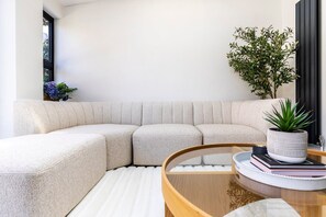Ein modernes Wohnzimmer mit einer Eckcouch, einem Glastisch und einem Blumentopf.
