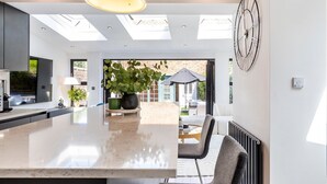 A modern kitchen with a central island, skylights, and a view to the outside. - Stylish Stamford Brook Garden Home (London)