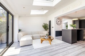 Una sala moderna con un sofá modular, una mesa de centro redonda y un ventanal grande.