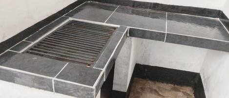 A corner of a room with a black and white tiled floor, a black drain, and a white wall.
