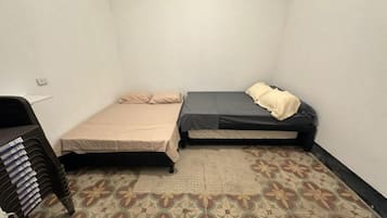 Eine kleine, einfache Unterkunft mit einem Bett, einem Sessel und einem Bücherstapel.