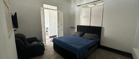 Un dormitorio con cama, ventilador de techo y ventana con persianas.
