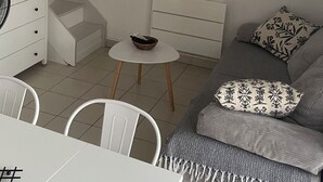 Ein modernes Wohnzimmer mit einer Couch, einem Esstisch, einem Fernseher und einer Pendelleuchte.
