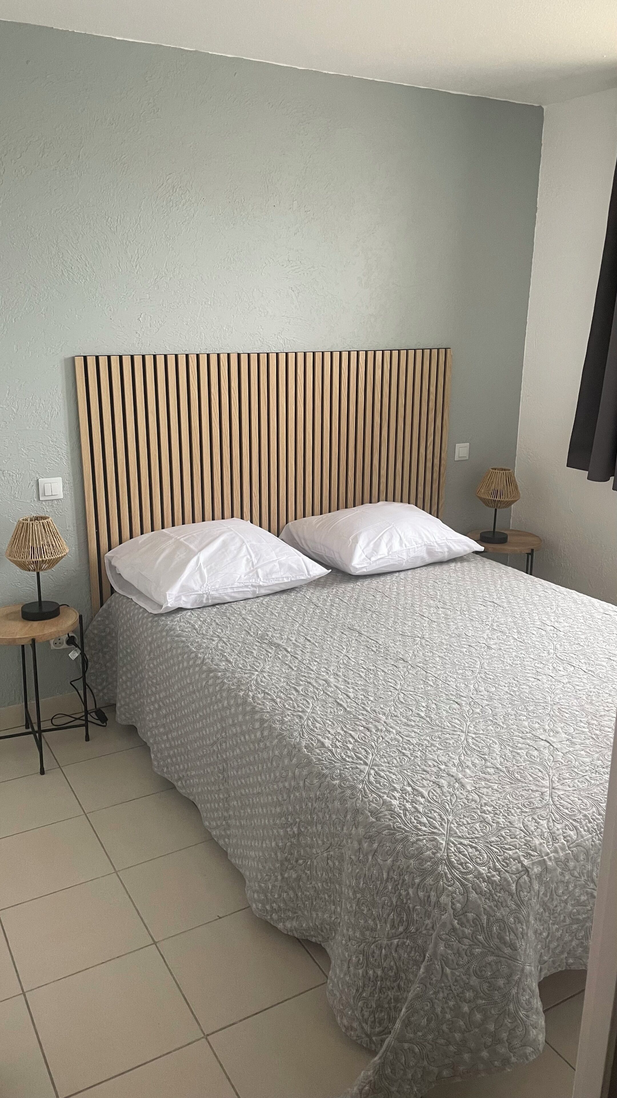 A bedroom with a bed, two bedside tables, and a headboard.