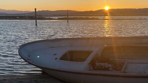 A boat on a sandy beach with a sunset in the background.