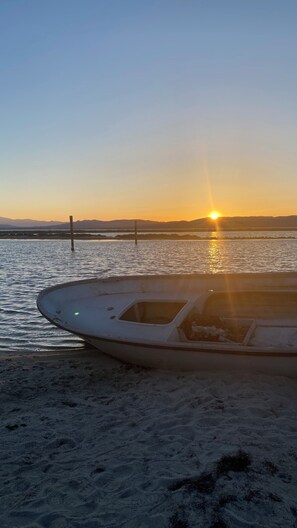 A boat on a sandy beach with a sunset in the background.