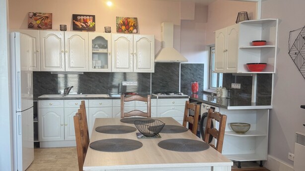 Una cocina moderna con armarios blancos, una mesa de comedor con individuales y piso de madera.