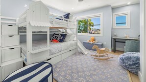 Een kinderstapelbed met een glijbaan, een schommelpaard en een raam met uitzicht.