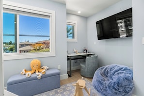 A room with a large window, a desk with a chair, a television, and a bean bag. - Santa Cruz Escape-Rooftop Deck/Ocean Views/Hot Tub (Santa Cruz)