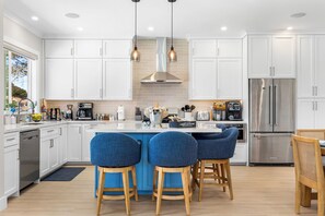 A modern kitchen with white cabinetry, stainless steel appliances, and a central island with bar stools. - Santa Cruz Escape-Rooftop Deck/Ocean Views/Hot Tub (Santa Cruz)