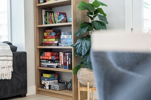 A bookshelf filled with various board games and a potted plant. - Santa Cruz Escape-Rooftop Deck/Ocean Views/Hot Tub (Santa Cruz)