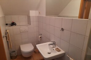 A small bathroom with a toilet, sink, and a mirror.