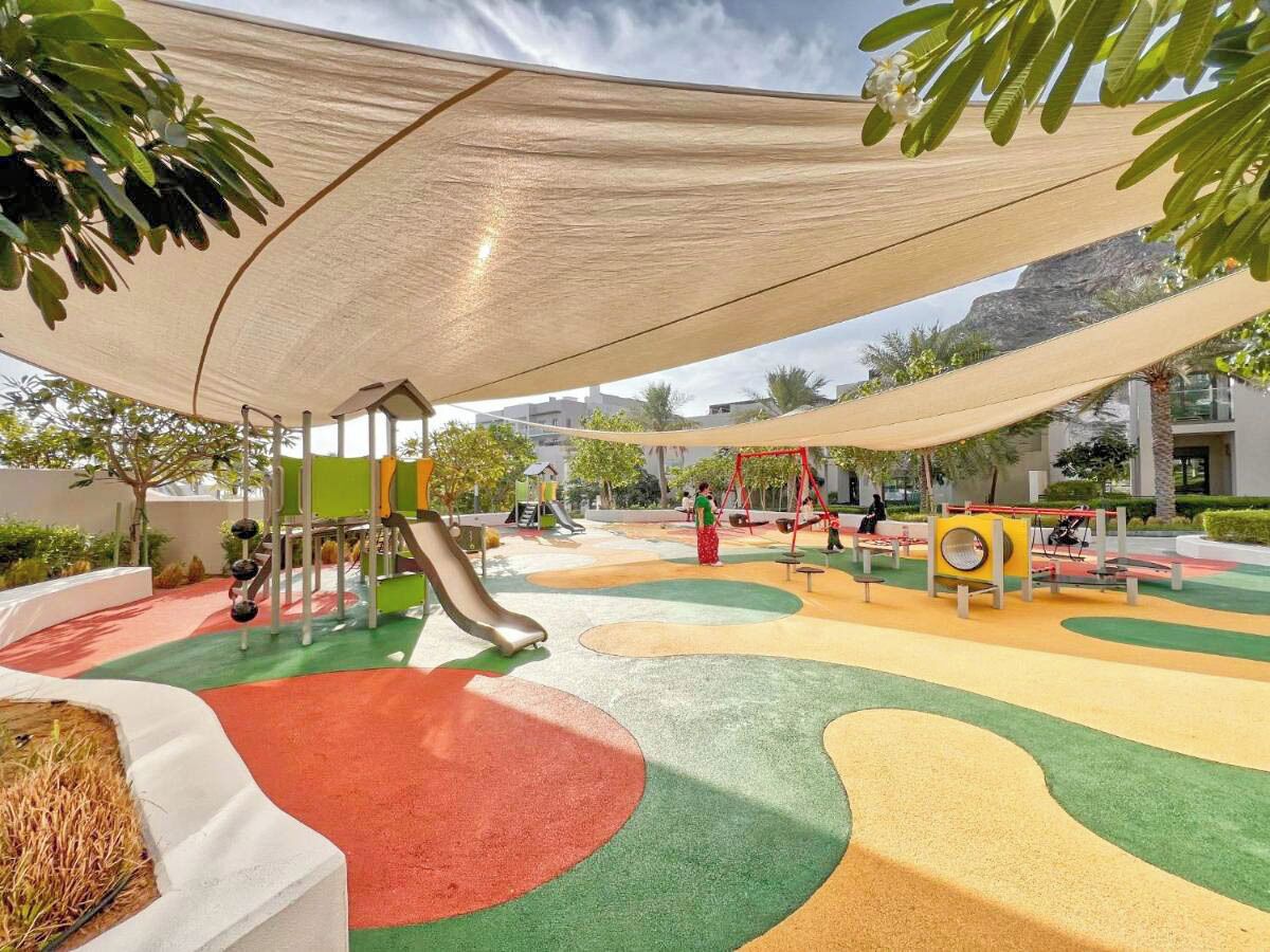 Une aire de jeux avec un toboggan, des balançoires et une structure d’escalade.