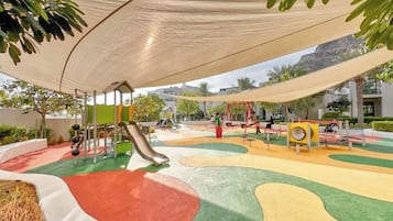 Une aire de jeux avec un toboggan, des balançoires et une structure d’escalade.