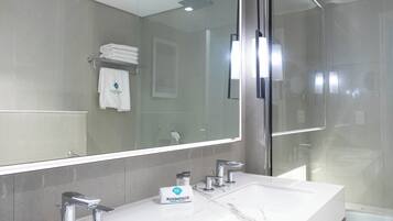 A modern bathroom with a large mirror, a white sink, and a glass shower enclosure.