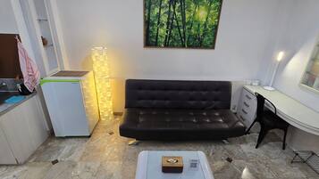 A compact kitchen with a refrigerator, a sink, and a dining area with a sofa and a small table.