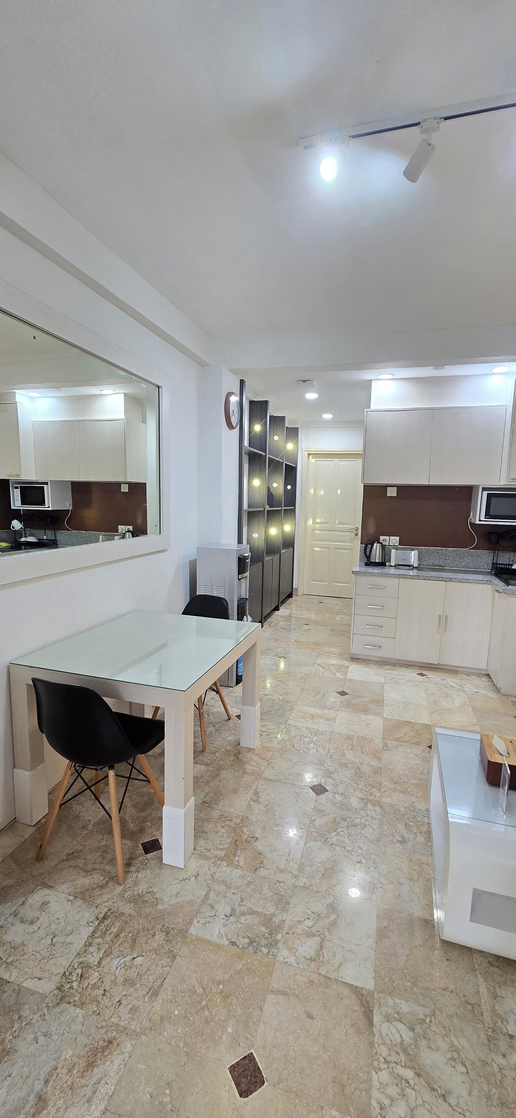 A modern kitchen with a dining area, marble flooring, and built-in appliances.