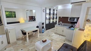 A compact living space with a kitchenette, a dining area, and a seating area. - Beach Resort Apartment. 5-Min Walk to Legian Beach (kuta)