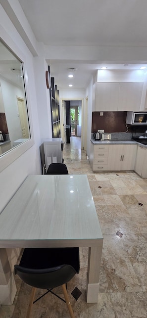 Una cocina moderna con comedor, que presenta piso de mármol, muebles de cocina blancos y un espejo grande.