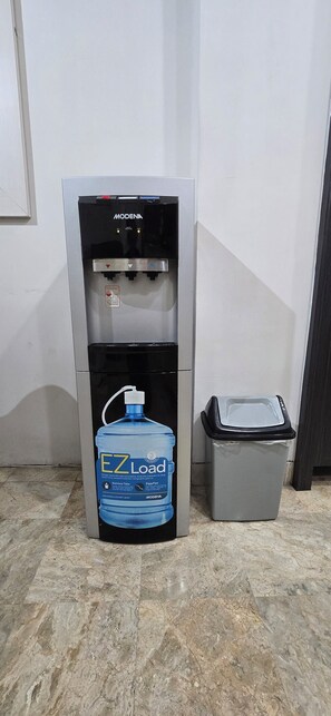 A water dispenser with a large water bottle beside it.