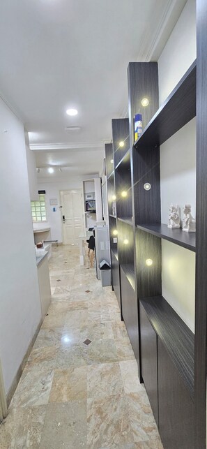 Un couloir doté d’un sol en marbre, un comptoir d’accueil et un espace détente avec des fauteuils.
