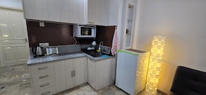 A compact kitchen with a microwave, toaster, sink, and a refrigerator.