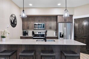 Una cocina moderna con una isla central, electrodomésticos de acero inoxidable y armarios de madera.
