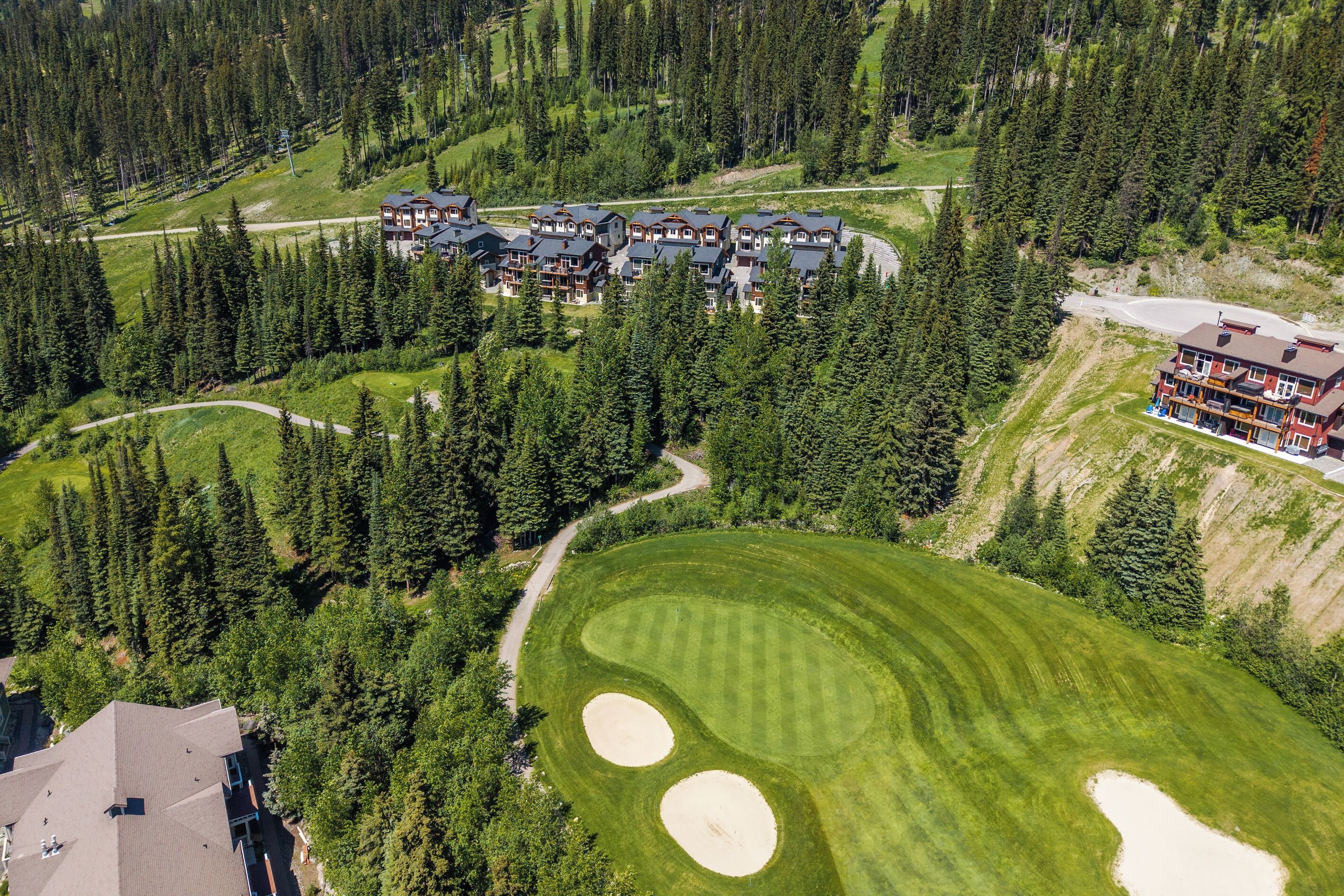 Un gran resort con varias edificaciones, un campo de golf y un bosque denso que lo rodea.