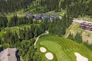 A large resort with multiple buildings, a golf course, and dense forest surrounding the property. - Cozy Alpine Condo w/Hot Tub! (Sun Peaks)