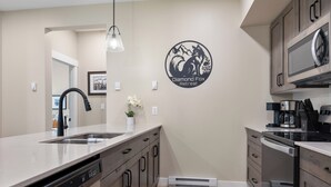 A modern kitchen with a dishwasher, stove, and microwave. - Cozy Alpine Condo w/Hot Tub! (Sun Peaks)