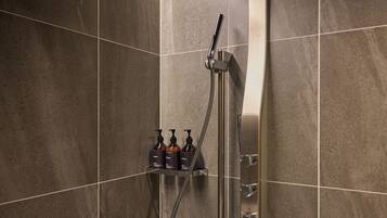 A shower with a handheld showerhead and a wall-mounted control panel.