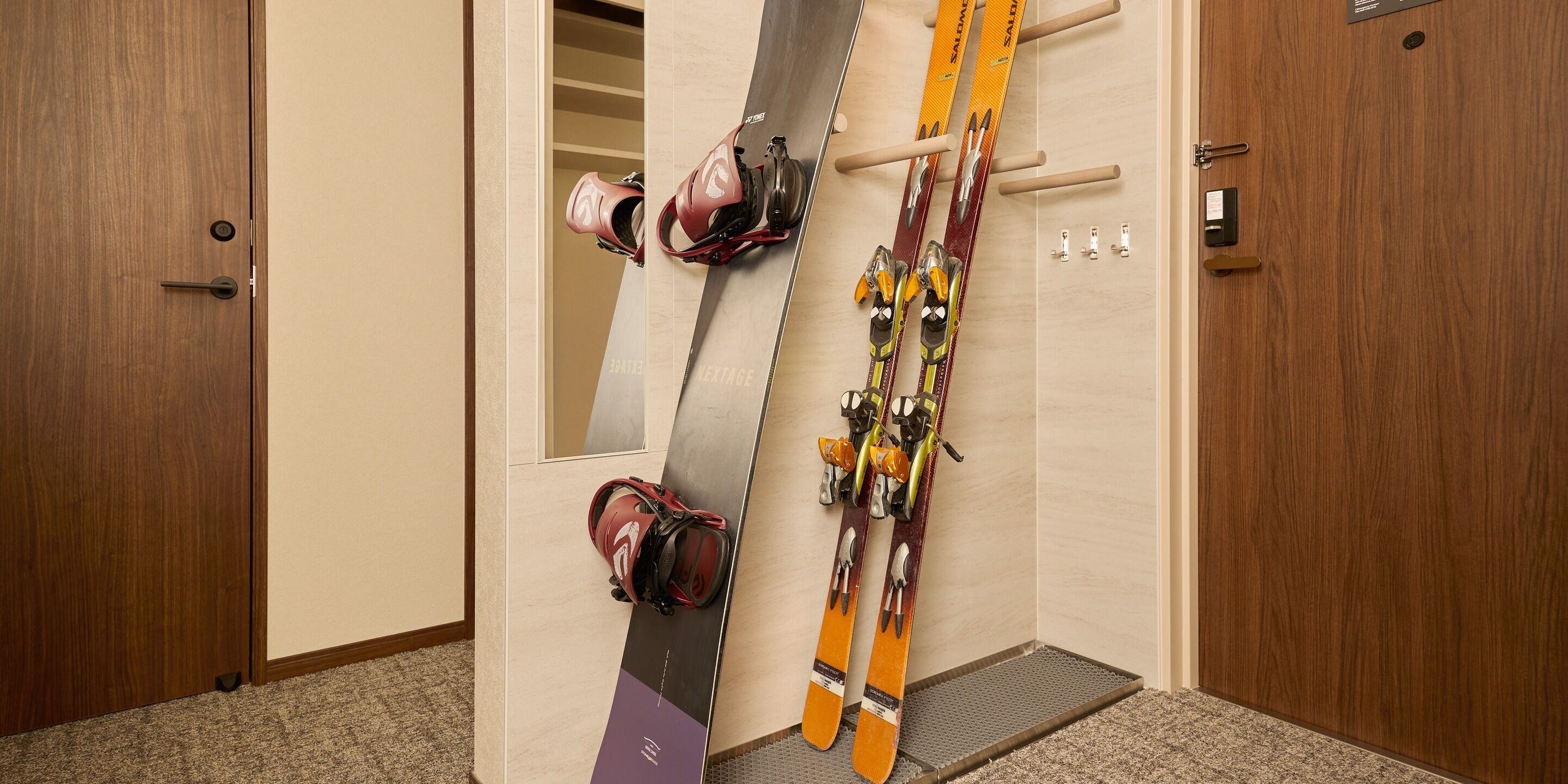 A room with a wooden door, a wall-mounted ski rack, and a carpeted floor.
